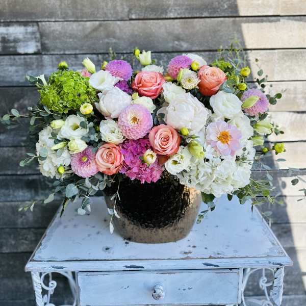 Mixed pink and white flower arrangement in a dark vase