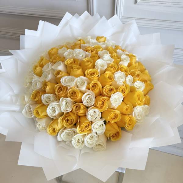 Bouquet of yellow and white roses wrapped in white paper