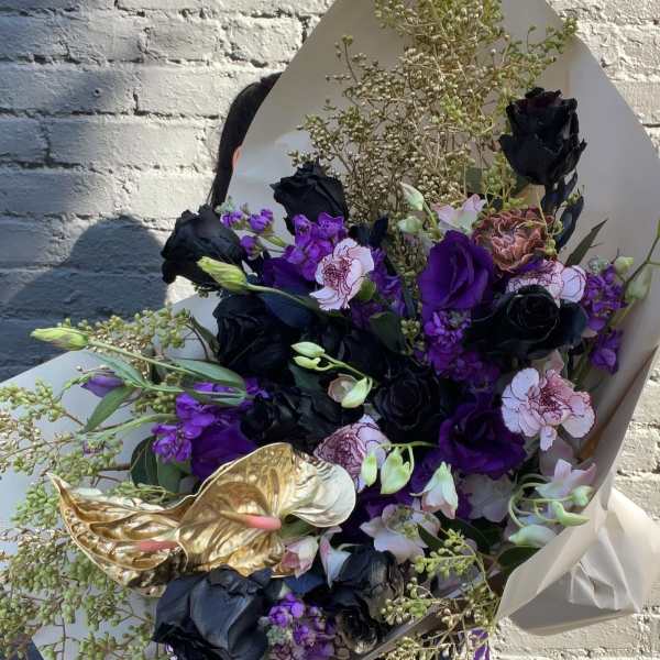 Bouquet of black, purple, and pale pink flowers with gold anthuriums