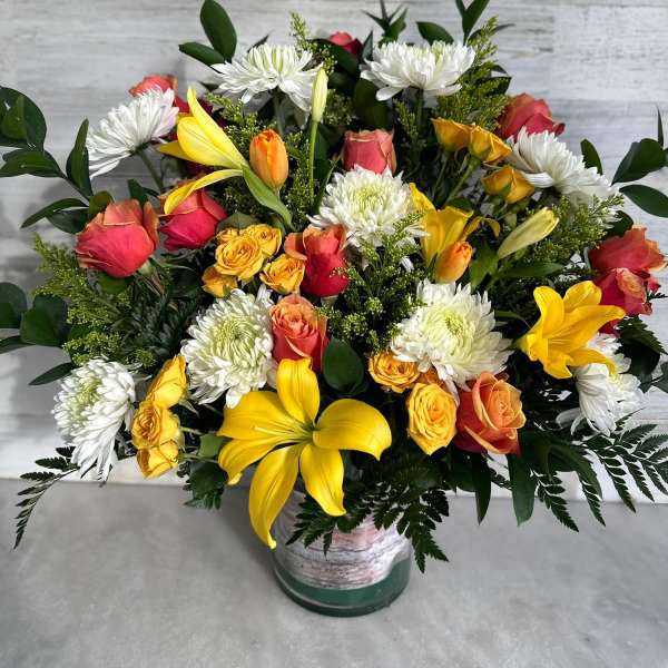 Mixed bouquet of yellow lilies, roses, and white chrysanthemums in a vase