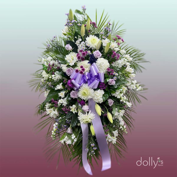 Standing floral spray with white and lavender flowers and a purple ribbon