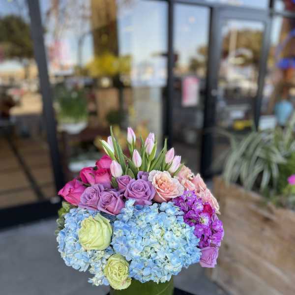 Bouquet of pastel roses, hydrangeas, and tulips in a green vase