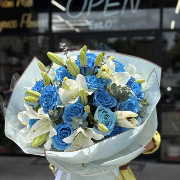 Bouquet of blue roses and white lilies wrapped in pale paper