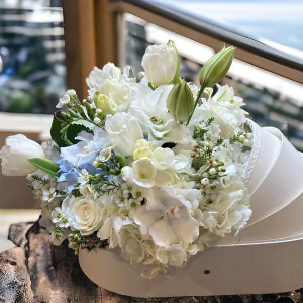 White floral bouquet with tulips and roses in a white hatbox
