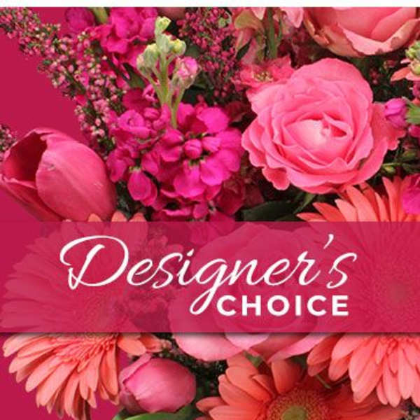 Pink floral arrangement with roses and daisies behind a Designer's Choice banner