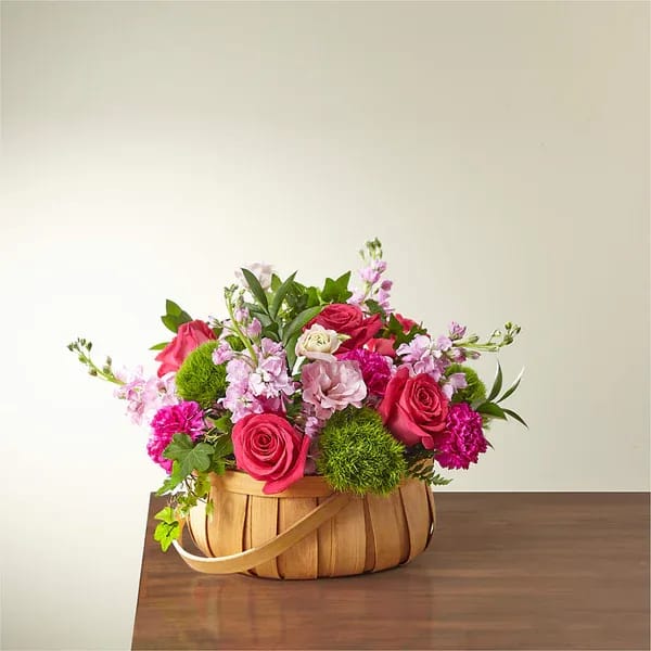 Pink and magenta flower arrangement in a woven basket