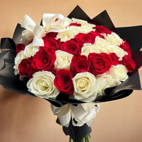 Bouquet of red and white roses wrapped in black paper with a white ribbon