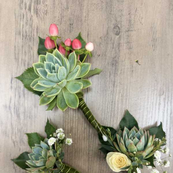 Three succulent boutonnieres with small roses and pink berry accents