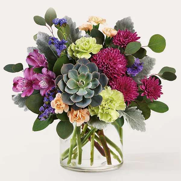 Mixed bouquet with a succulent in a clear glass vase