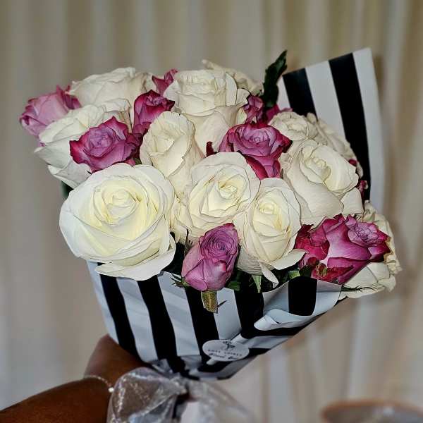 Bouquet of white and pink roses wrapped in black-and-white striped paper