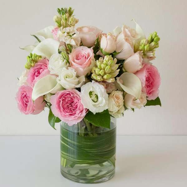 Pink and white roses with calla lilies in a glass vase