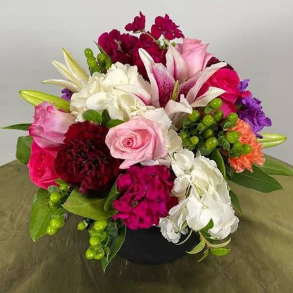 Mixed bouquet of pink, white, purple, and red flowers in a black vase