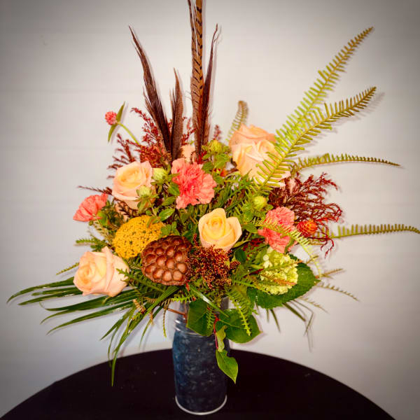 Peach roses and coral carnations in a tall blue vase