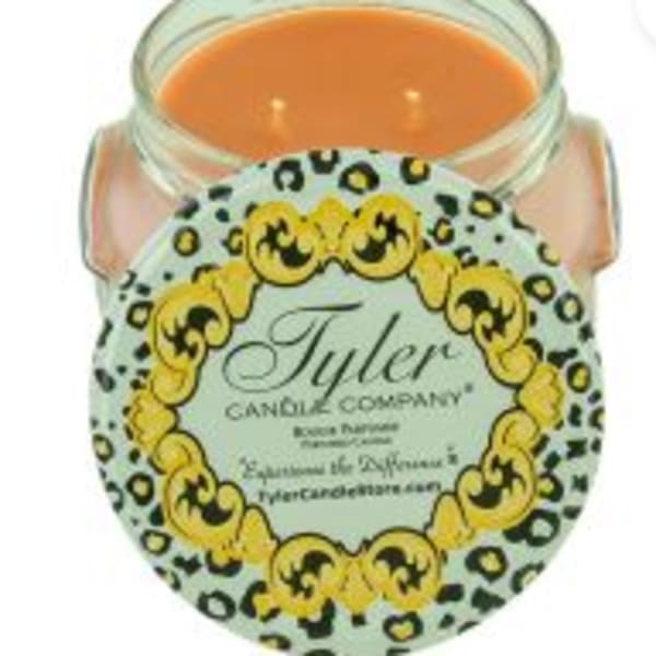 Orange candle in a glass jar with a decorative label