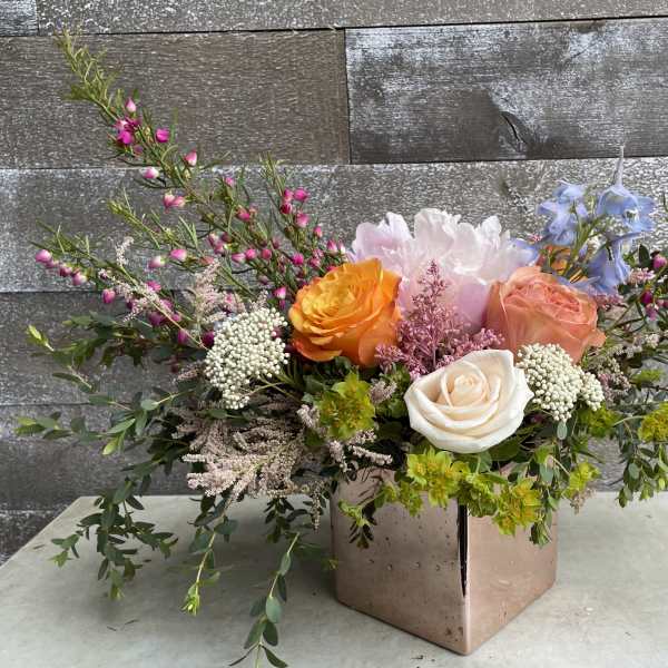 Mixed bouquet with roses and pastel blooms in a square vase