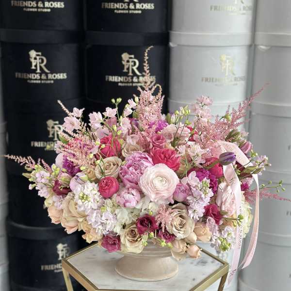 Pink and cream rose arrangement in a pedestal vase with ribbon