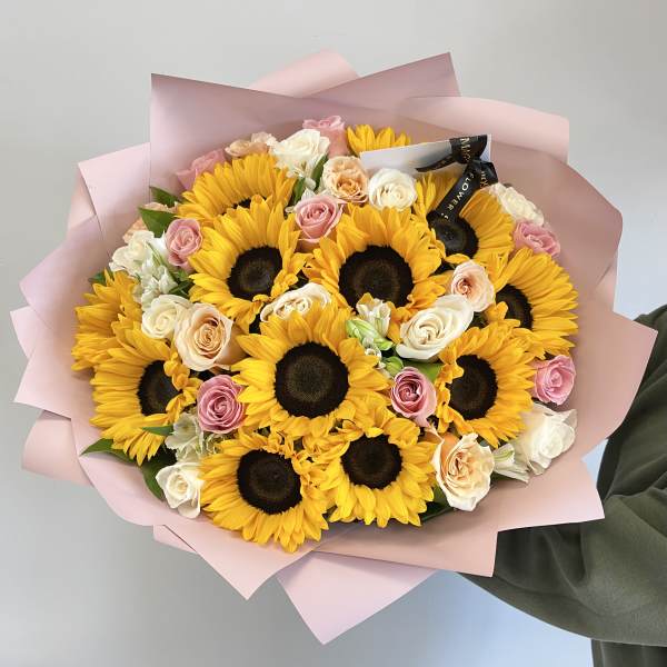 Bouquet of sunflowers and pastel roses wrapped in pink paper