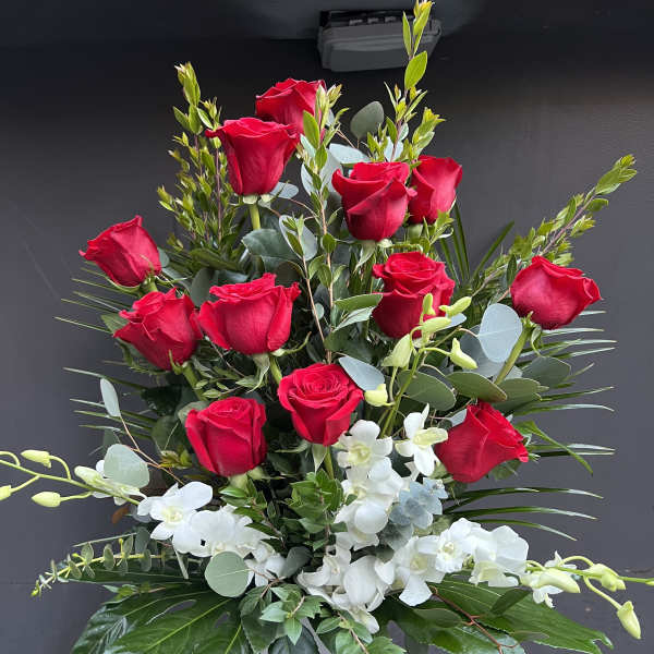 Tall arrangement of red roses and white orchids in a white vase