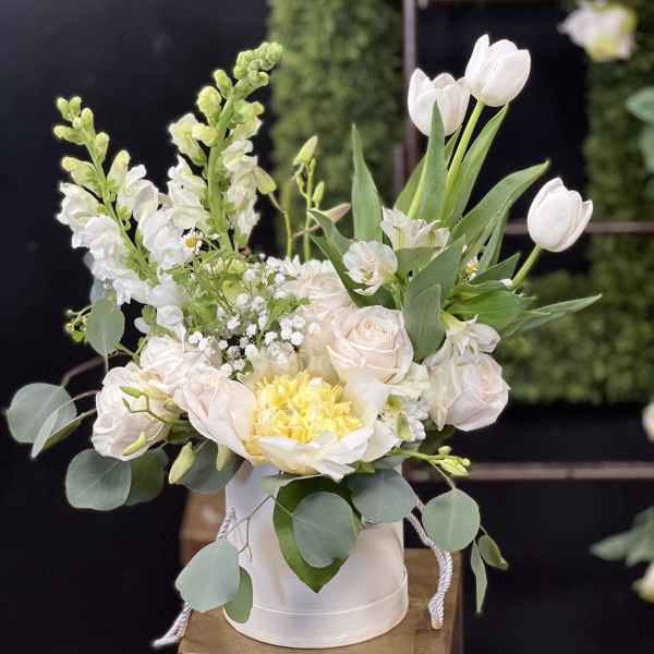 White and pale blush floral arrangement in a round white box