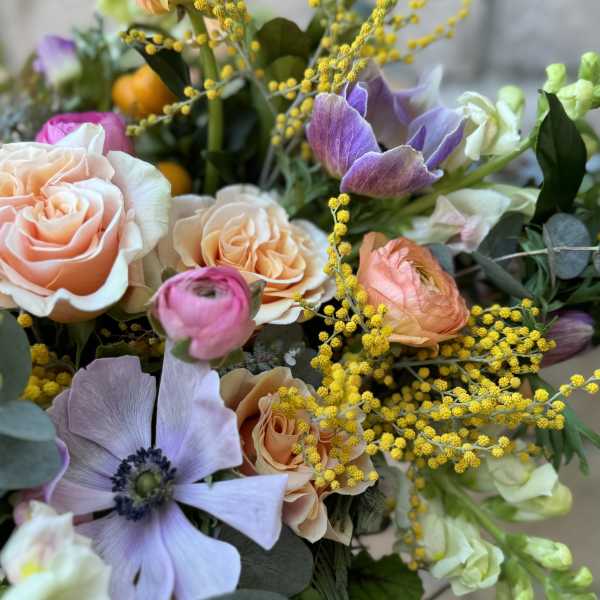 Bouquet of peach roses and purple anemones with yellow filler flowers