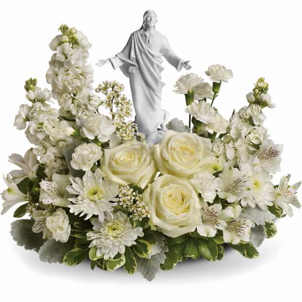 White floral arrangement with a small statue of Jesus in the center