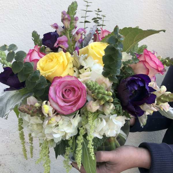 Bouquet of pink and yellow roses with white blooms in a glass vase