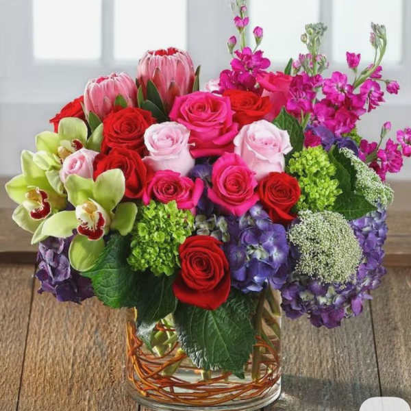 Mixed bouquet of roses, orchids, and hydrangeas in a glass vase