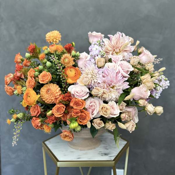 Mixed bouquet of orange, pink, and cream flowers in a ceramic vase