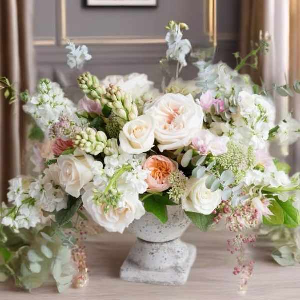 Pastel floral arrangement in a stone pedestal vase