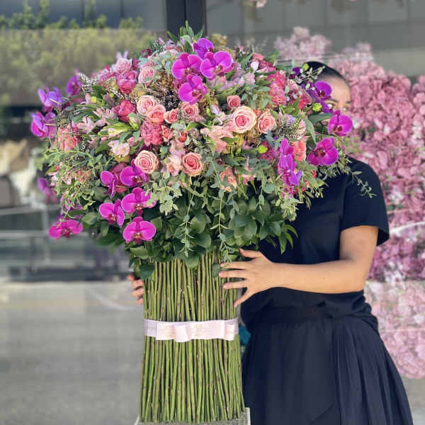 Large bouquet of pink roses and purple orchids held by a person