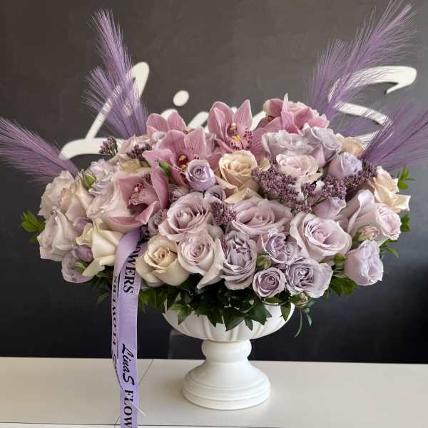 Lavender and blush rose arrangement in a white pedestal vase