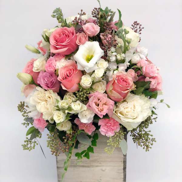 Pink and white rose and carnation arrangement in a rustic wooden box