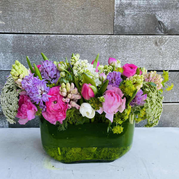 Mixed pink and purple flowers arranged in a green glass vase