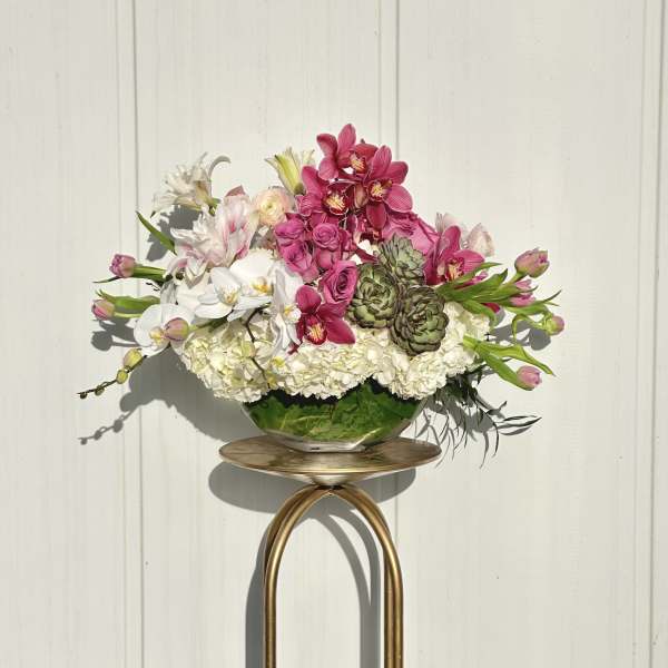 Pink and white floral arrangement in a glass bowl on a gold stand
