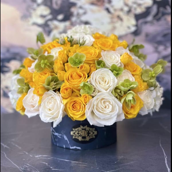 Yellow and white rose bouquet in a dark round box