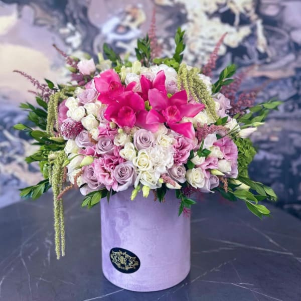 Pink and white floral arrangement in a lavender hat box