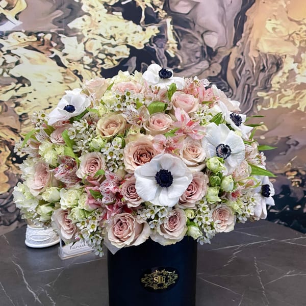 Large bouquet of blush roses and white anemones in a black hat box