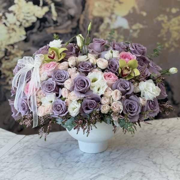 Lavender and pink rose arrangement in a white vase with a ribbon bow