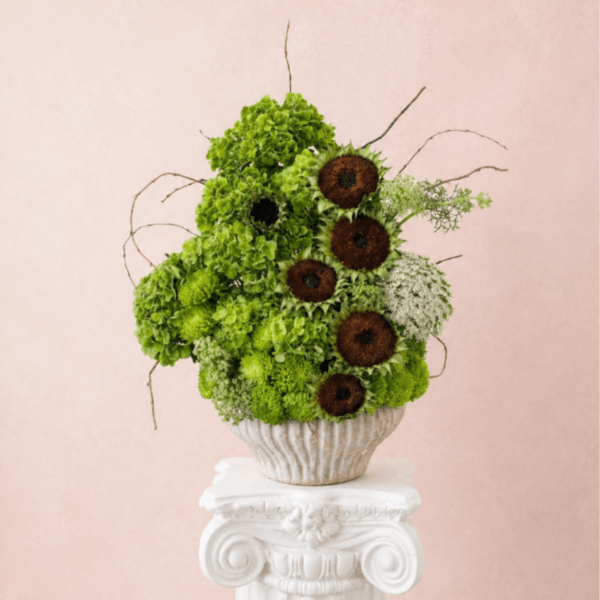Green floral arrangement with dark sunflower centers in a textured vase