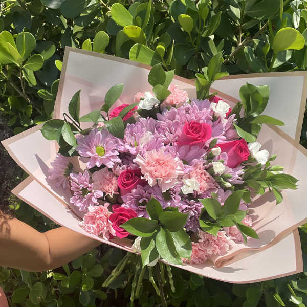 Pink and lavender bouquet with roses and daisies in pale wrapping