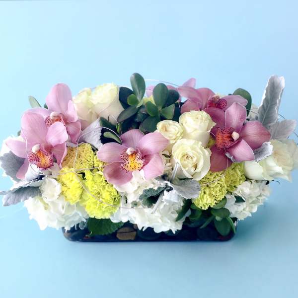 Pink orchids and white roses in a low rectangular arrangement