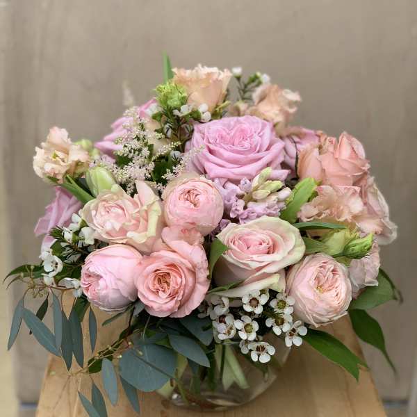 Pink roses and blush flowers arranged in a glass vase