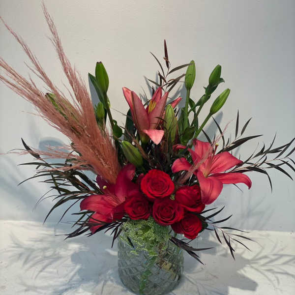 Red roses and pink lilies arranged in a glass vase