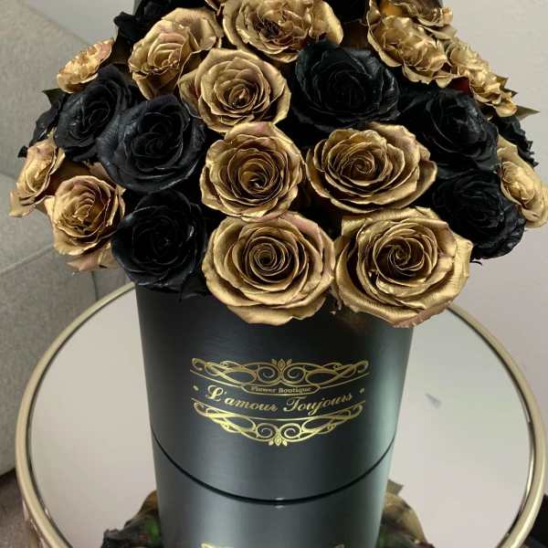 Black and gold roses arranged in a tall black hat box with gold lettering