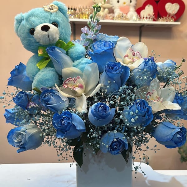 Blue rose bouquet with white orchids and a blue teddy bear in a white vase