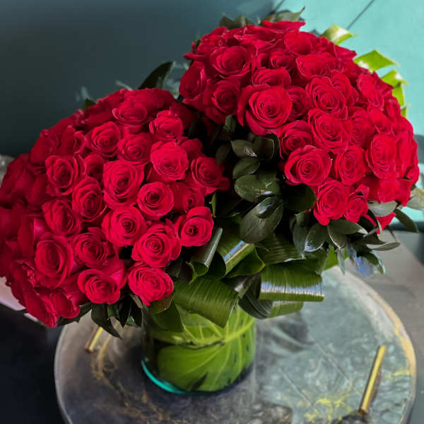 Two large bouquets of red roses in a glass vase