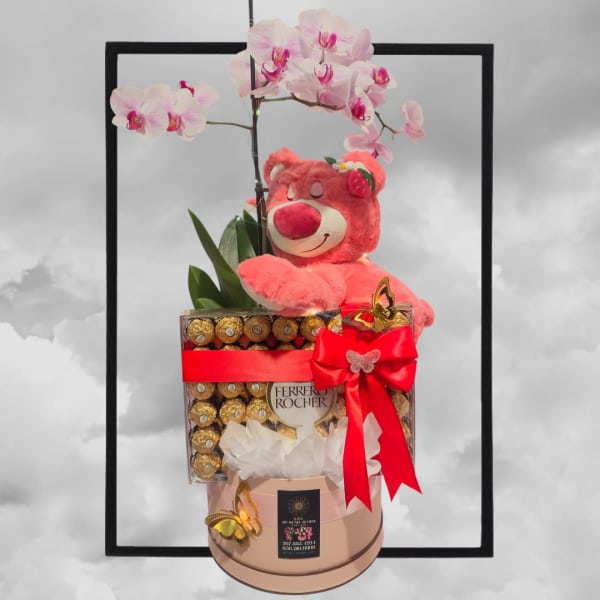 Pink orchid stems with a teddy bear and chocolate box gift arrangement
