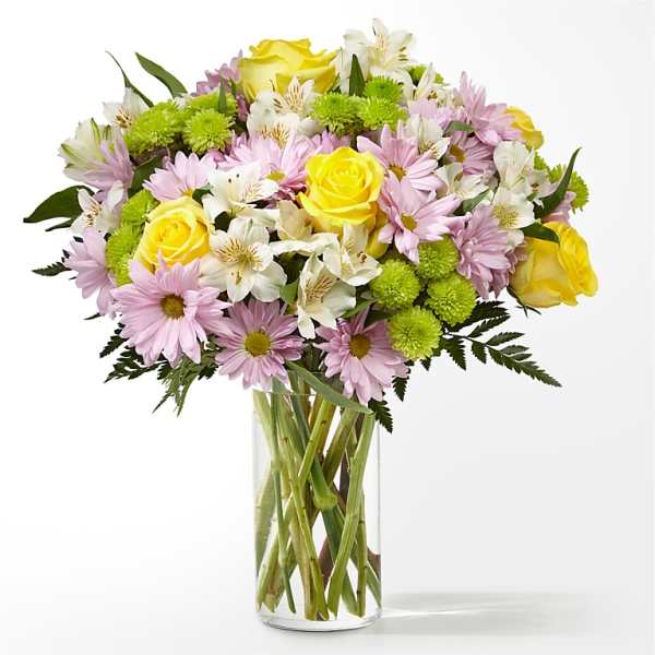 Bouquet of yellow roses, pink daisies, and white alstroemeria in a glass vase