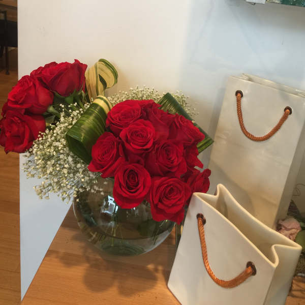 Two red rose bouquets in a glass vase with baby's breath