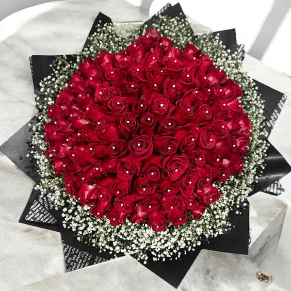 Round bouquet of red roses with white baby's breath in black wrap